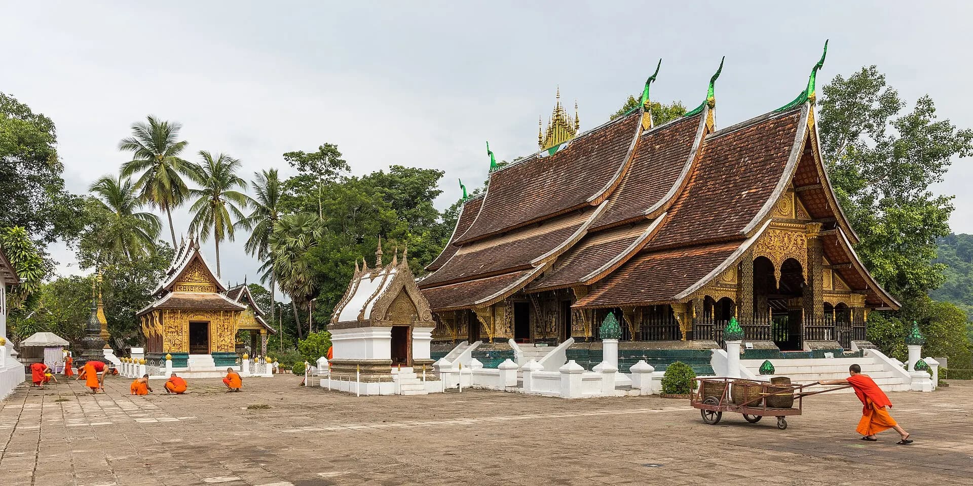 Buddhist monks cleaning the yard at Wat Xieng Thong temple