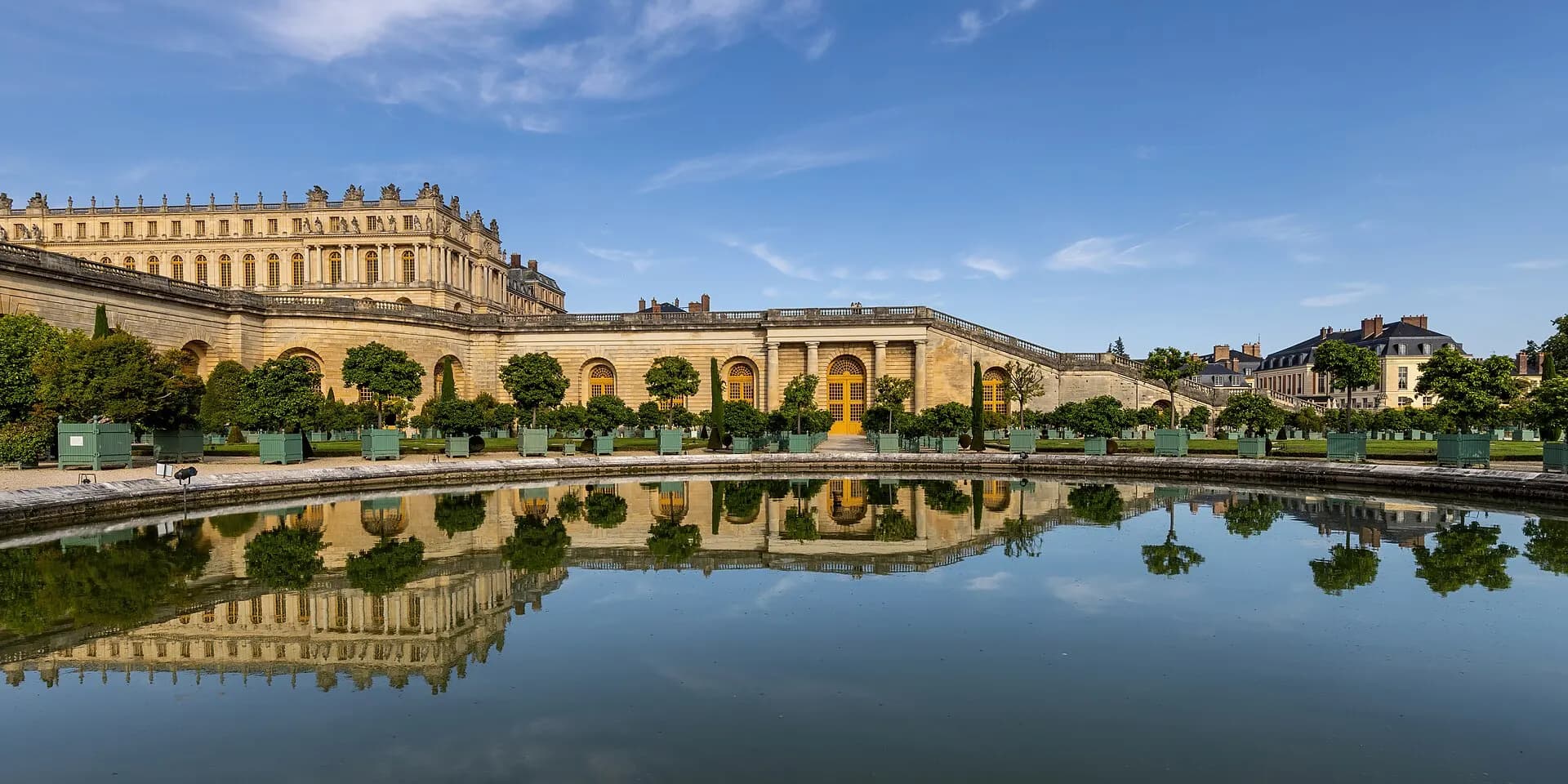 Water reflection of the Orangerie garden and Palace of Versailles with blue sky in France